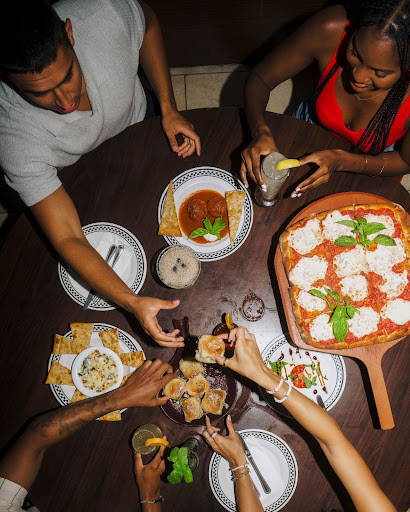 A group of people enjoying coal-fired pizza and wings at an Easter celebration from Anthony’s Coal Fired Pizza & Wings.
